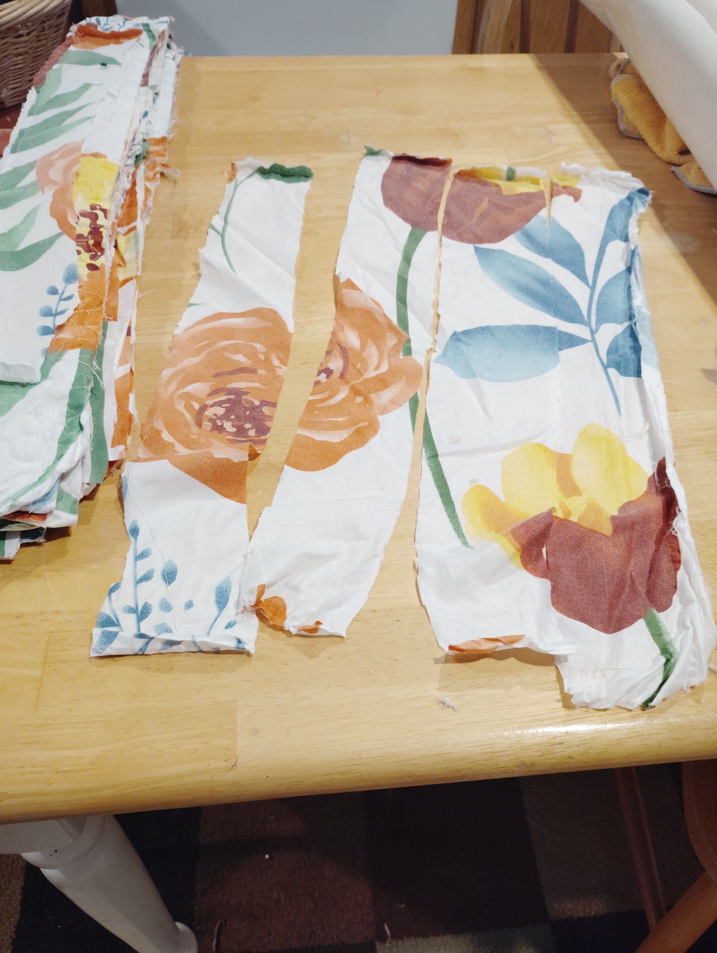 The first Soul Cloth cuttings spread across a wooden table, with floral fabric strips torn and laid out for sorting